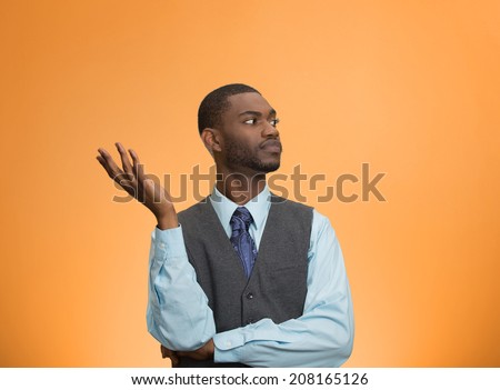 Closeup portrait dumb clueless young executive man, arm out asking why what problem so who cares, I don\'t know, isolated orange color background. Negative human emotion facial expression feelings