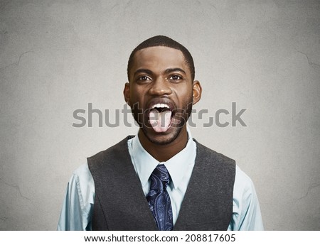 Closeup portrait funny, annoyed, young business man, employee sticking out his tongue, isolated grey background. Human face expressions, emotions, attitude, body language, life perception, reaction