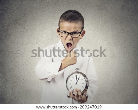 Closeup portrait, Angry, Mad, pissed off Child, Boy, playing boss manager, Screaming, about to smash alarm clock with fist, isolated grey wall background. Negative human emotions, facial expressions