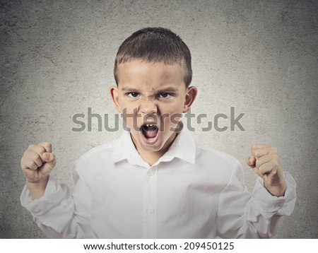 Closeup Portrait Angry child, Boy Screaming fists up in air, demanding justice, his rights isolated grey wall background. Negative human Emotion, Facial Expression, body language, attitude, perception