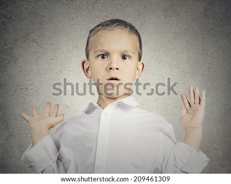 Closeup portrait headshot scared child, boy hands up in air, opened mouth looking at you camera, isolated grey wall background. Human facial expressions, emotions, feelings, body language, perception