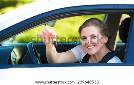 Closeup portrait happy, smiling, attractive woman, buyer sitting in her new white car showing keys isolated outdoors street dealership lot background. Personal transportation, auto purchase concept