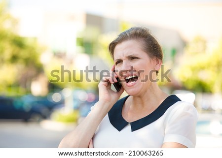 Portrait Angry Woman Screaming while Talking on mobile Phone, isolated outdoors parking lot background. Negative human emotions, facial expressions, feelings, attitude. Bad communication concept