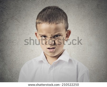 Closeup portrait Angry, displeased child Boy looking at you camera, mad about something, isolated grey wall background. Negative human emotions, feelings, facial expression, perception, body language