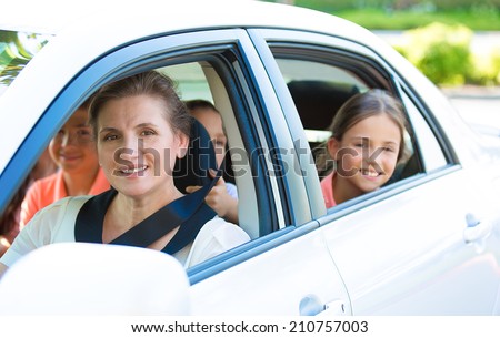 Portrait happy, smiling Family, mother, three kids sitting in the white, silver car looking out windows, ready for vacation trip, outdoor background. Positive Human face expression, emotions, feelings