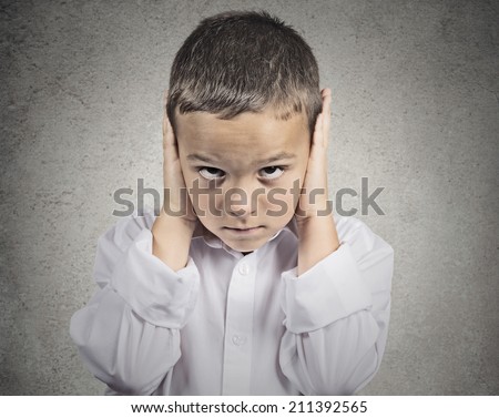 Closeup portrait, headshot child, boy covering ears with hands, doesn\'t want to hear loud noise, conversation isolated grey wall background. Human face expression, emotion, feeling reaction perception