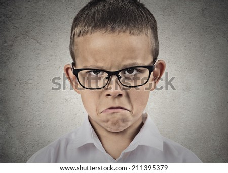 Closeup portrait unhappy, sad, child, funny looking boy in white shirt, with glasses isolated grey wall background. Negative human emotions, facial expressions, feelings, life perception, reaction