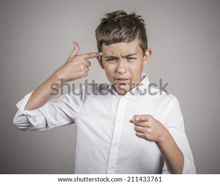 Closeup portrait rude difficult angry young man gesturing with finger against his temple, are you crazy? Isolated grey wall background. Negative human emotion, facial expression, feeling body language