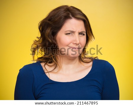 Closeup portrait skeptical young woman looking suspicious, some disgust on her face mixed with disapproval isolated yellow background. Negative human emotion facial expression feeling body language
