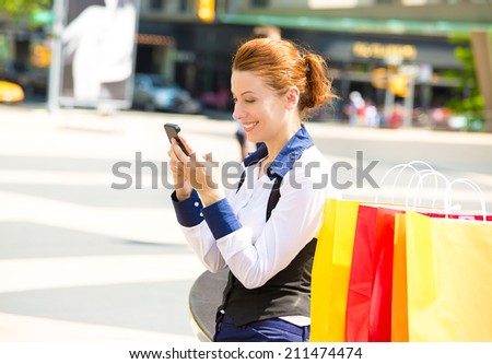 Shopping woman in New York City. Beautiful, happy, summer shopper with yellow shopping bags, smiling texting on phone, outside street background. Positive emotions. Caucasian model in Manhattan, USA.