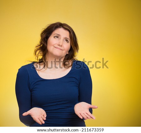 Closeup portrait dumb young woman, arms out asking what\'s problem, who cares so what, I don\'t know. Isolated yellow background space to right. Negative human emotion, facial expressions, body language