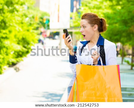 Closeup portrait shocked shopper woman looking at her smart phone, discovered great online deal, sale, receiving surprising news isolated outside new york city background. Emotions, facial expression