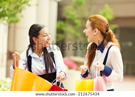 Portrait two happy, laughing young women showing each other what they bought in shopping mall, isolated outdoor street background. Positive human emotions, feeling, face expressions, lifestyle