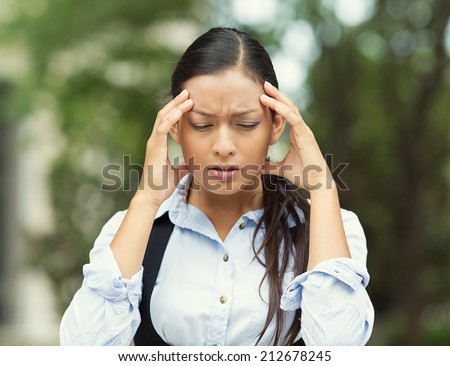 Closeup portrait unhappy young business woman hands on head stressed bothered by mistake having bad headache migraine isolated outdoor park background. Negative human emotion facial expression feeling