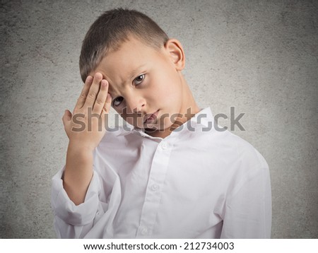 Young man suffering from headache. Closeup portrait little boy having a head ache, isolated grey wall background. Negative human face expressions, emotions, feelings, body language, life perception
