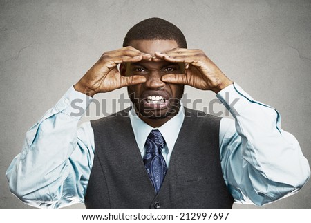 Closeup portrait young, curious funny man, looking through his fingers like binoculars, searching something, unhappy disgusted with future forecast isolated grey wall background. Human face expression