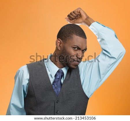 Closeup young man, smelling sniffing his armpit, something stinks bad, foul odor isolated orange background. Negative human facial expressions, feeling body language, perception. Personal hygiene
