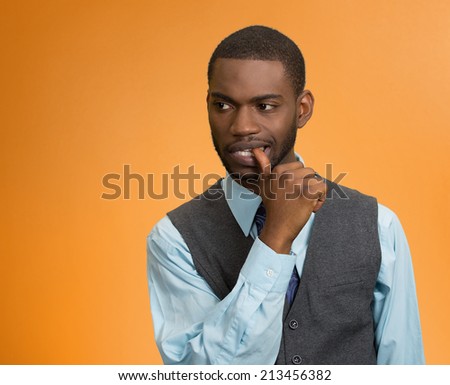 Closeup portrait, man with finger in mouth, sucking thumb, biting fingernail in stress, deep thought, isolated orange background. Negative human emotions, facial expressions, feelings, reaction
