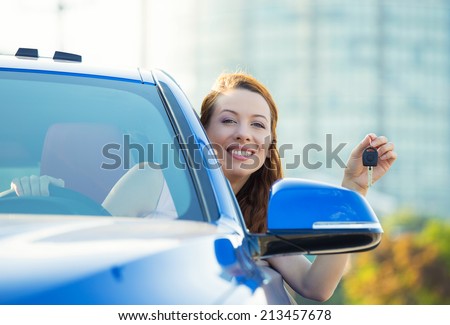 Closeup portrait happy, smiling, young attractive woman, buyer sitting in her new blue car showing keys isolated outside dealer, dealership lot, office. Personal transportation, auto purchase concept