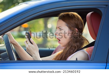 Closeup portrait, young shocked, stressed woman driver, driving in car checking smart phone annoyed by bad text message email isolated outside street background. Negative human emotion face expression
