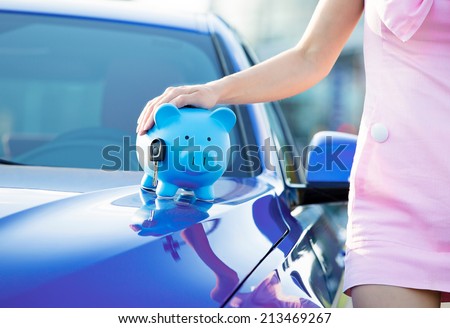 Cropped image woman customer, agent and new car, piggy bank, key on hood, isolated outside, outdoors. Dealership offering credit line, finance services. Lease, automobile purchase, financing concept