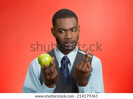 Stressed businessman deciding on healthy life choices, craving cigarette versus green apple isolated red background. Face expression, body language, bad, hazardous human habits