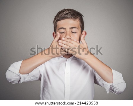 Portrait young man, student, boy, covering his mouth with hands. Speak no evil concept, isolated grey wall background. Human emotions, face expressions, feelings, signs, surrounding perception