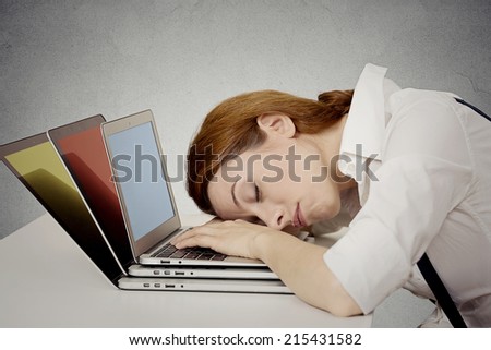 Sleeping woman at her desk, on computer, busy day, schedule, too much to do, grey wall background