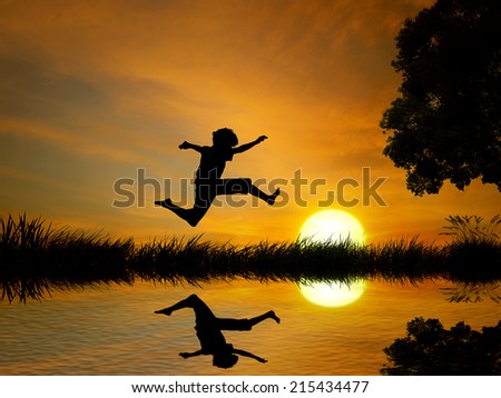 Happy boy, teenager jumping in water, over lake with sunset background, body reflection in water. Outdoor exciting summer vacation, travel life, leisure. Lifestyle freedom concept
