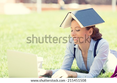 Young female student using laptop outdoor, laying down on green grass on sunny summer day outside. Positive human emotions, face expressions, feelings, happy college life style