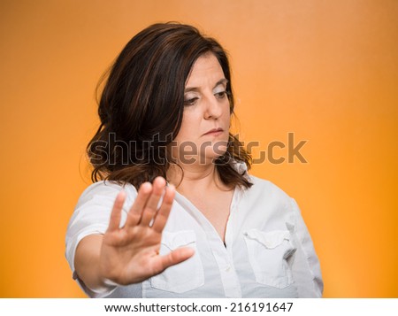 Offended. Portrait middle age grumpy woman with bad attitude giving talk to my hand gesture with palm outward, isolated orange background. Negative emotions, facial expression feelings, body language