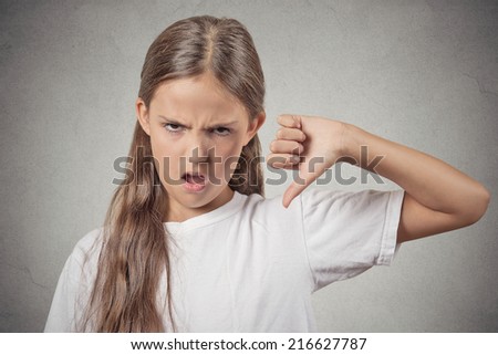 Thumbs down. I don\'t like it. Portrait unhappy, Angry, Displeased Child isolated grey wall background. Negative human Face Expressions, Emotions, Feelings, attitude, life perception, body language