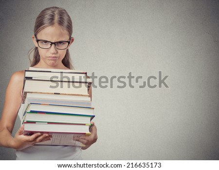 Too much to learn! Unhappy teenager girl, student holding huge stack of books, looks displeased, isolated on grey wall, chalkboard background with copy space. Human face expressions, emotions, feeling