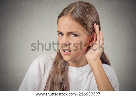 I can\'t hear you speak up. Closeup portrait unhappy hard of hearing teenager placing hand on ear asking someone to repeat or listening bad news isolated grey wall background. Emotion facial expression