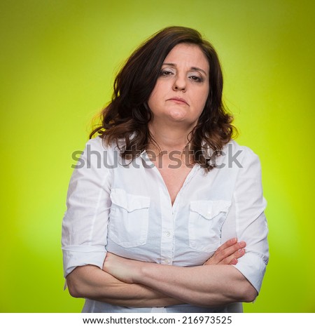 Portrait displeased pissed off angry grumpy woman with bad attitude, arms crossed looking at you, isolated green background. Negative human emotion facial expression feeling body language