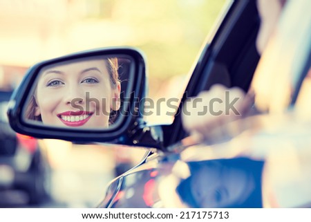Happy young woman driver looking in car side view mirror, making sure line is free before making a turn. Human facial expressions, emotions. Safe trip, journey driving concept