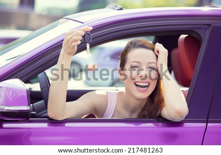 Closeup portrait happy, smiling, young attractive woman, buyer sitting in her new purple car showing keys isolated outside dealer, dealership lot office. Personal transportation, auto purchase concept