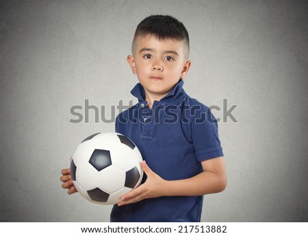 Future soccer player. Boy holding football ball isolated grey wall background. Confident face expression