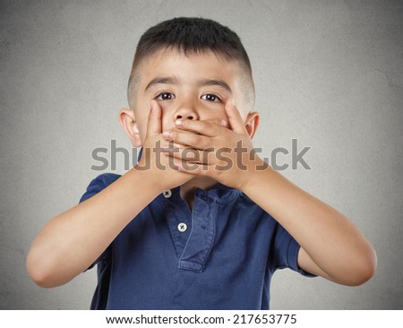 Closeup portrait young handsome man, boy closing, covering mouth with hands can\'t speak hiding isolated grey wall background. Speak no evil concept. Human emotion facial expression feeling reaction