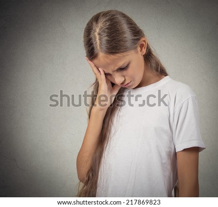 Closeup portrait sad depressed tired disappointed child resting face on hand looking down isolated grey wall background. Negative human emotion face expression feeling life perception body language