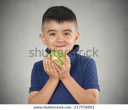 Happy child boy eating green apple smiling isolated grey wall background. Positive human emotions, face expressions. Healthy diet, food, nutrition concept