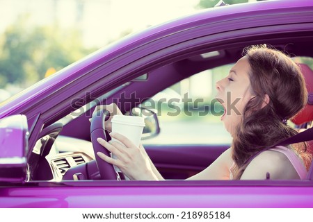 Closeup portrait sleepy, tired, fatigued, exhausted young attractive woman driving her car after long hour trip, isolated street traffic background. Transportation, sleep deprivation, accident concept