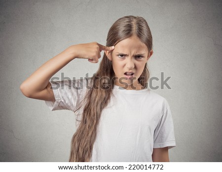 Closeup portrait angry mad teenager girl gesturing with her finger against temple asking are you crazy? Isolated grey wall background. Negative human emotions facial expression feeling body language