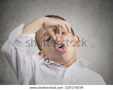 Closeup portrait child boy with disgust on face pinches his nose something stinks bad smell situation isolated grey wall background. Negative human emotions facial expressions perception body language