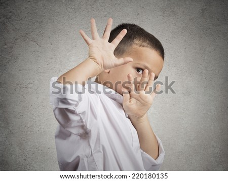 Closeup portrait child boy looking shocked scared trying to protect himself from unpleasant situation, object thrown at him isolated grey wall background. Negative emotion facial expression feeling