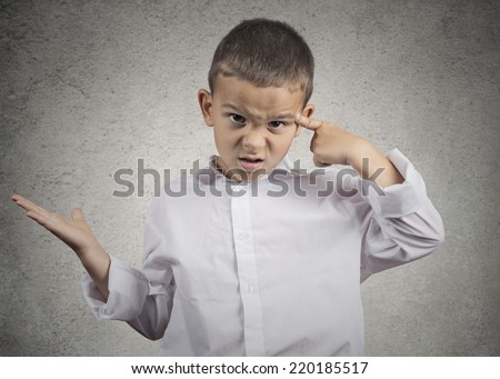 Closeup portrait angry mad child boy gesturing with his finger against temple asking are you crazy? Isolated grey wall background. Negative human emotions facial expression feeling body language