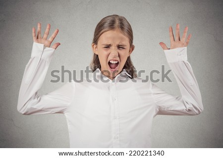 portrait angry teenager girl screaming, wide open mouth, hysterical isolated grey wall background. Negative human face expressions, emotion, bad feelings reaction. Conflict, confrontation concept