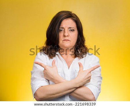 Closeup portrait confused middle aged woman pointing in two different directions, not sure which way to go in life isolated yellow background. Negative emotion facial expression feeling body language