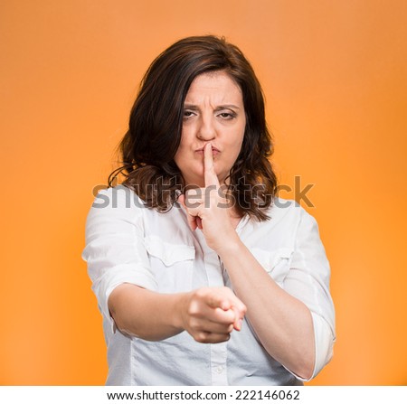Quiet, patronize. Closeup portrait middle age woman placing finger on lips with shhh sign symbol, asking silence isolated orange background. Negative emotion facial expression feelings, body language
