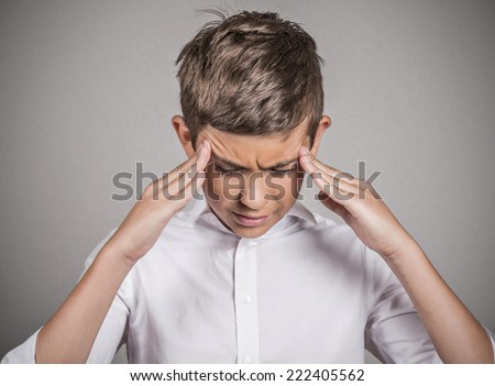 Closeup portrait stressed sad teenager boy hands on temples, head spinning around, overwhelmed at school in life isolated grey background. Negative human facial expression emotion feeling, perception